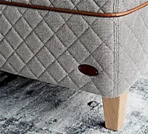 Detail of the DUX 3003 bed and tapered bed legs on a light green carpet. 
